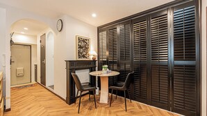 A dining area with a round table, two chairs, a clock on the wall, and a decorative piece on the table. - Designer-style 2-bedroom apartment & large living room Max 7people Shinjuku 501 (新宿区)