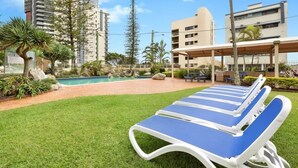 A poolside area with lounge chairs, a small pool, and a building in the background.