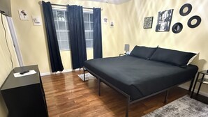 Un dormitorio con cama, escritorio, silla y ventana con cortinas.