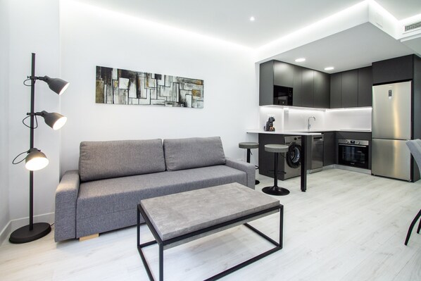 Una sala de estar moderna con un sofá gris, una mesa de centro y una lámpara de pie.
