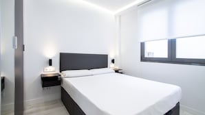 Un dormitorio moderno con cama, mesitas de noche y ventana.