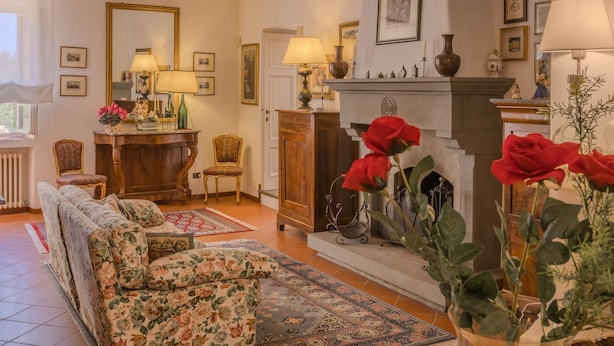 A traditional living room with a fireplace, floral sofas, and a variety of decorative items.
