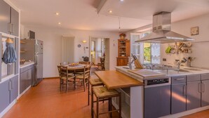 A modern kitchen with a central island, stainless steel appliances, and a dining area with wooden chairs and a table.