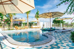 A swimming pool with lounge chairs and umbrellas, surrounded by palm trees and a patterned floor. - Mia Hot Springs Pool Villa Binh Chau (Ho Chi Minh City)