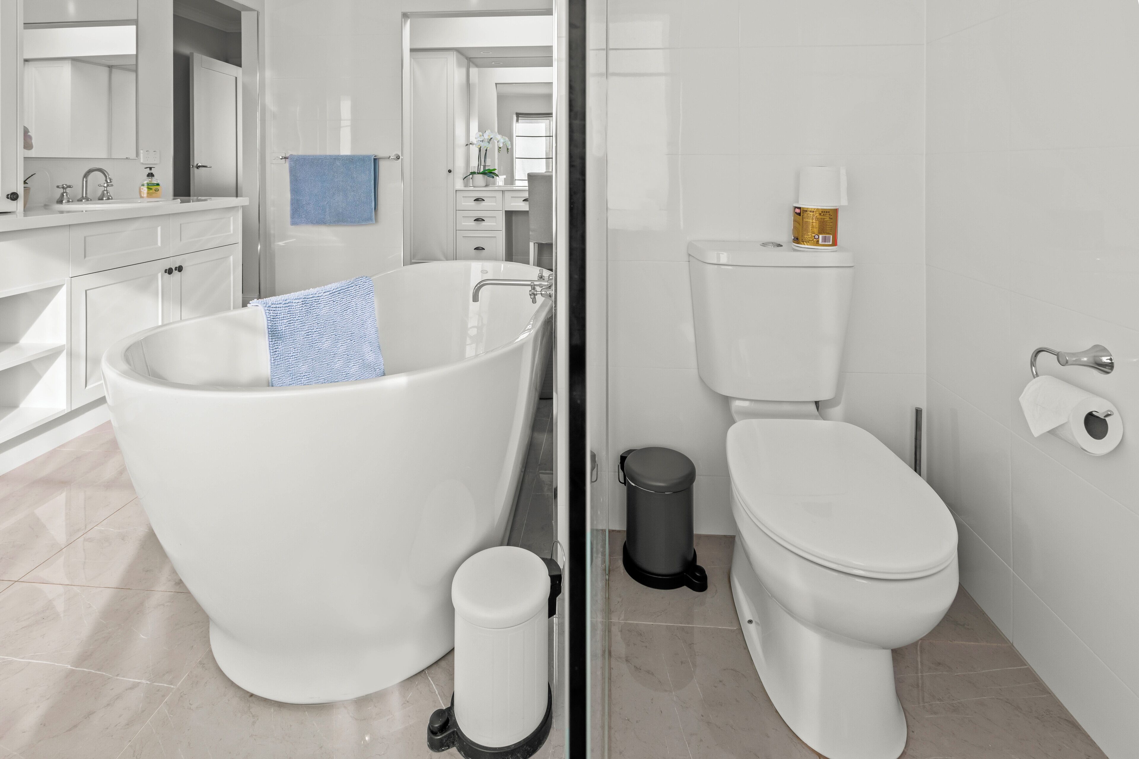 A modern bathroom with a freestanding bathtub, a toilet, and a trash bin.