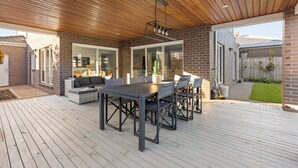 A covered patio with a wooden ceiling, a dining table with chairs, and a sofa. - StayAU Contemporary 5BRM Families Home Point Cook (Point Cook)