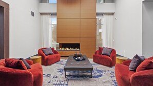 A modern living room with a fireplace, red sofas, and a coffee table. - Luxury King Bed+Pool+Gym+DowntownATX+Domain+Q2Stadium (Austin)