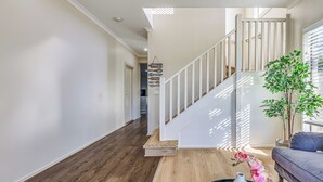Een modern interieur met een houten vloer, een wenteltrap met witte leuningen, een kamerplant en een bank.