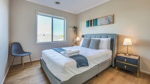 Een slaapkamer met een groot bed, een stoel, een nachtkastje en een raam.