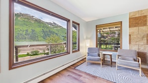 A room with large windows, a fireplace, and a view of a mountainous landscape.