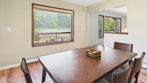 A spacious dining area with a large table, chairs, and a view of a lake through a large window.