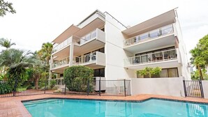 A modern multi-story hotel with a swimming pool, balconies, and lush greenery. - Beachfront Location -Ground Floor. Listen to the waves! (Mooloolaba)