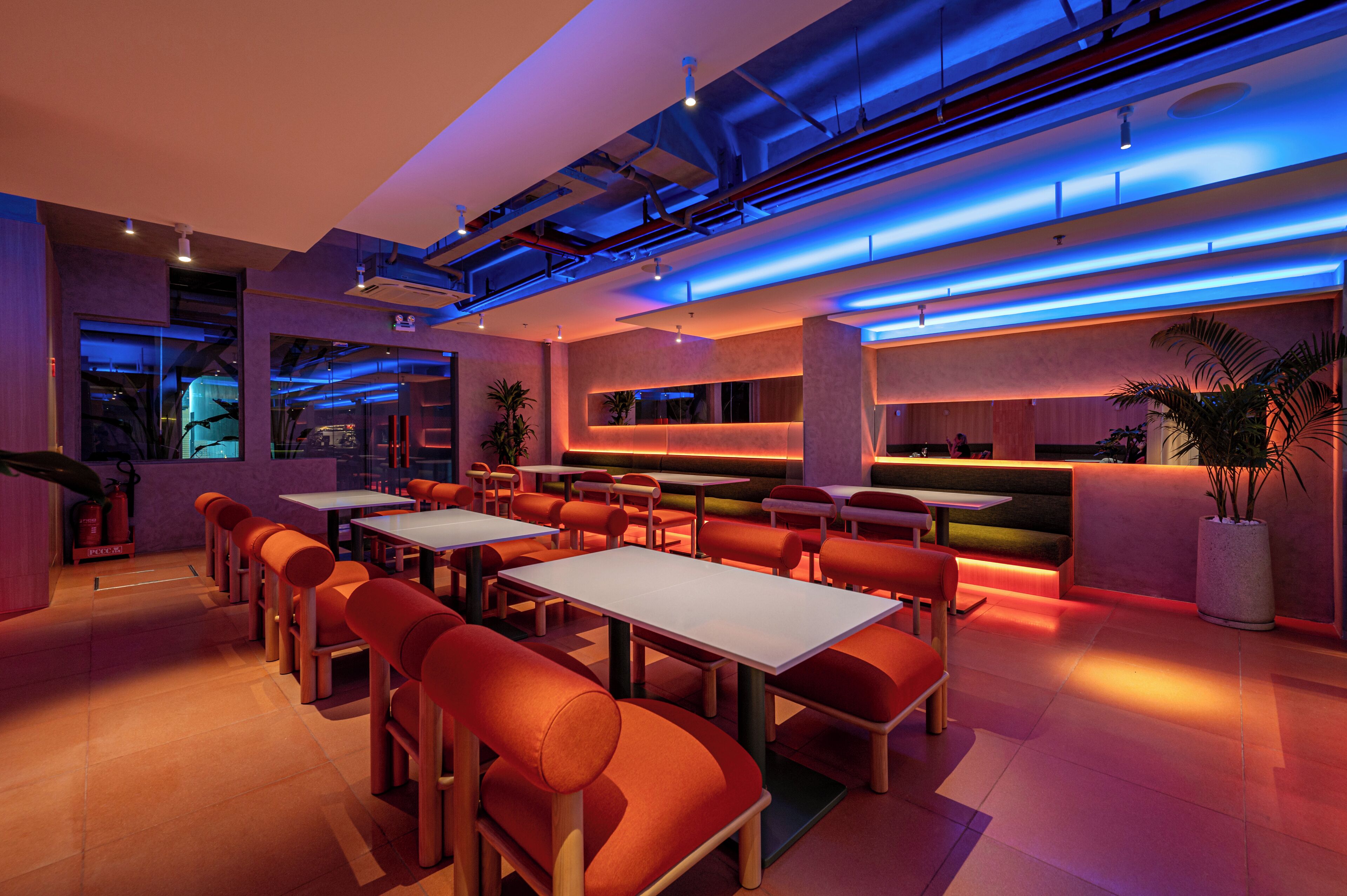 A modern restaurant with a bar area, seating arrangements, and a visible fire extinguisher.