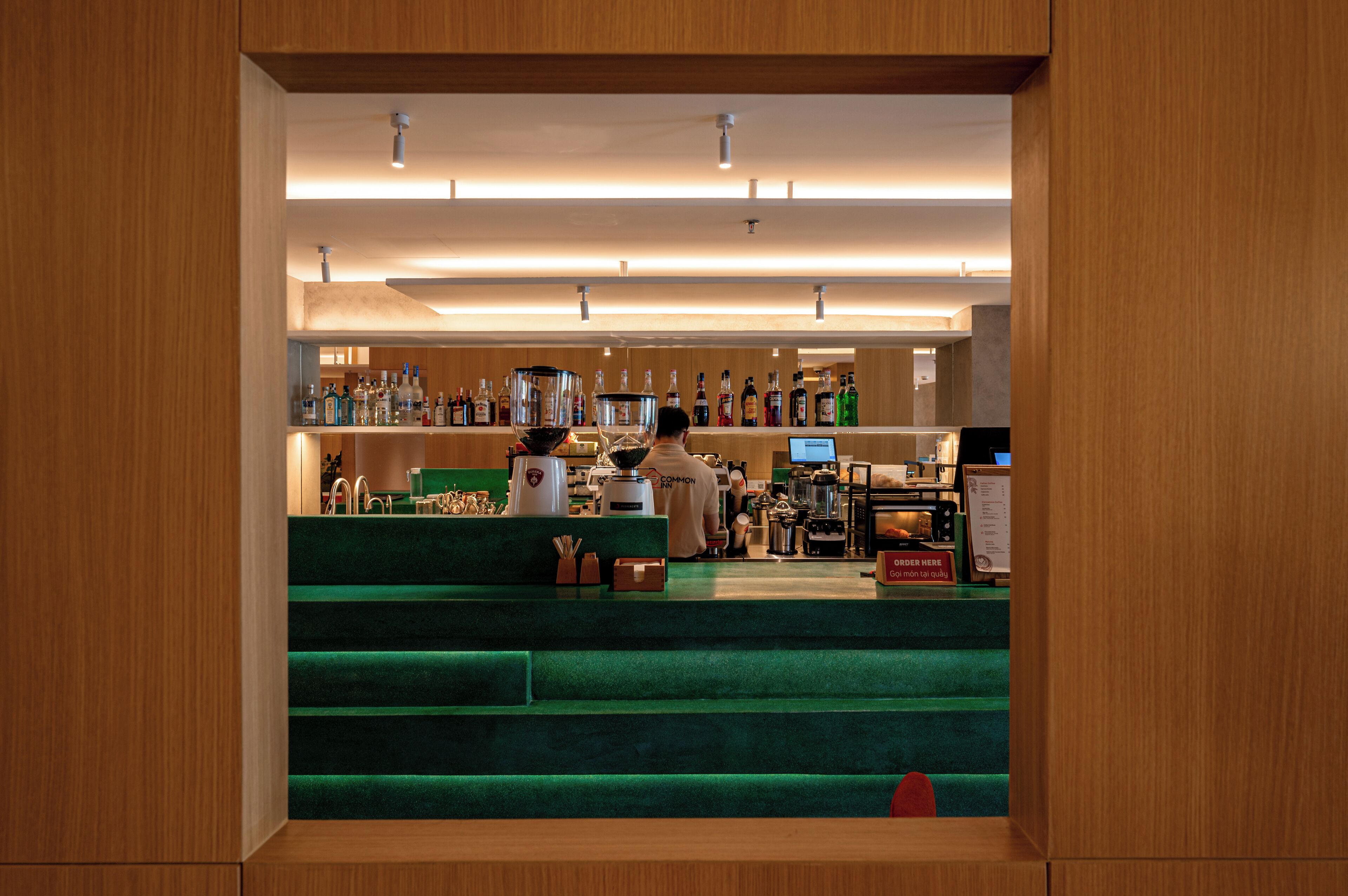 Uma área de bar com balcão, banquetas e diversas garrafas.