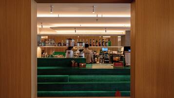 Uma área de bar com balcão, banquetas e diversas garrafas.