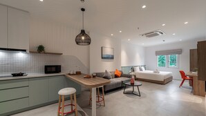 Una cucina moderna con isola centrale, zona pranzo con sgabelli, divano e un letto in camera da letto.
