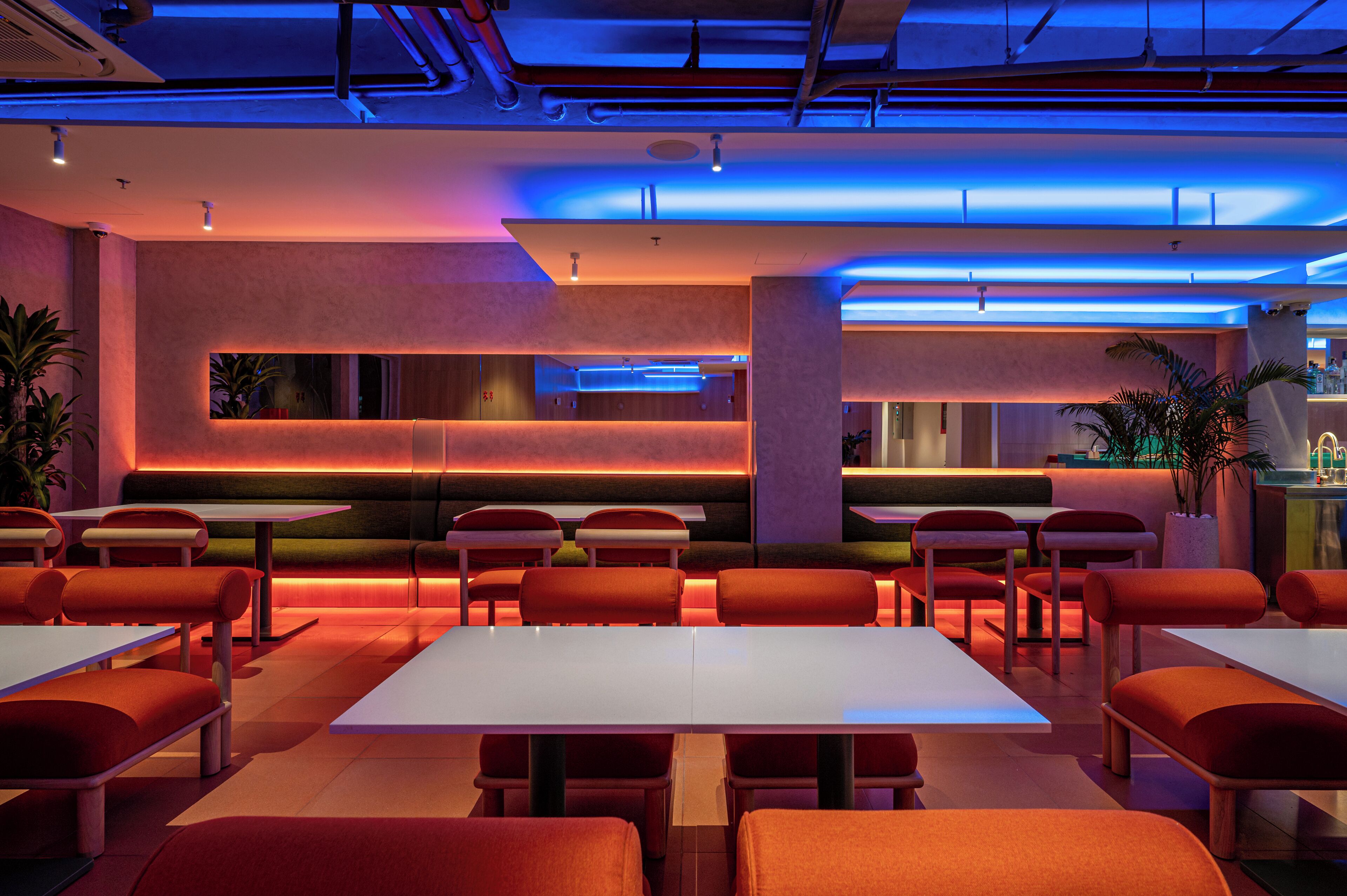 A modern restaurant with a long counter and multiple seating areas.