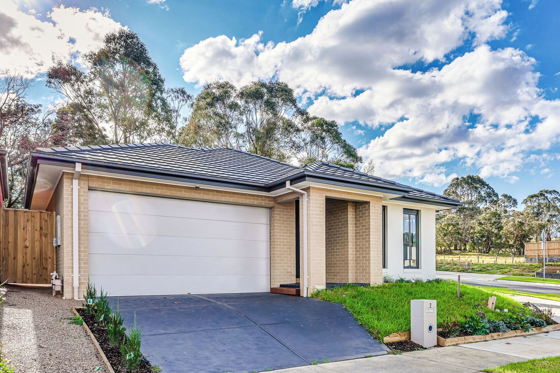 A modern two-story house with a garage, a driveway, and a well-maintained garden.