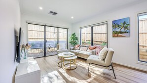 A spacious living room with a sofa, coffee table, and a TV on a stand. - StayAU Officer Newly 5BRM Homley Villa House (Officer)