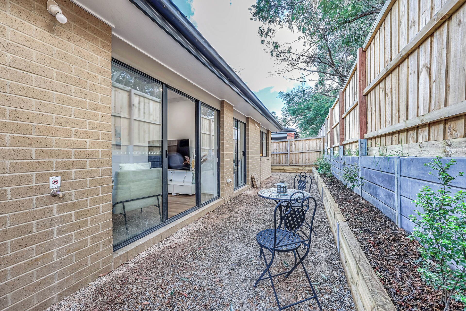 A patio area with a table and chairs, a brick wall, and a wooden fence.