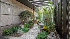 Ein Garten mit einem Kiesweg, verschiedenen Pflanzen und einer traditionellen Steinlaterne.