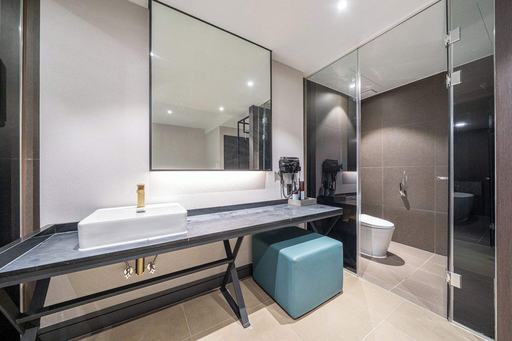 A modern bathroom with a large mirror, a sink, a toilet, and a shower area.
