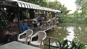 Een restaurant aan de rivier met terras en een overdekt eetgedeelte.