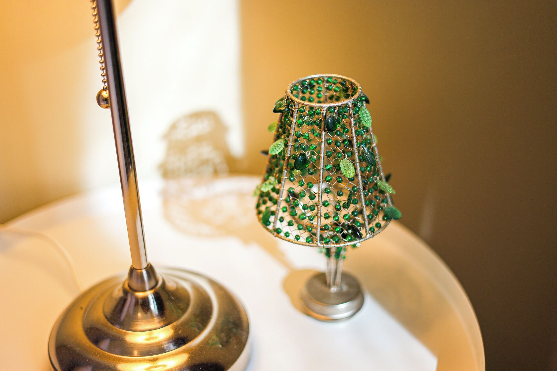 A lamp with a metallic base and a decorative green glass shade.