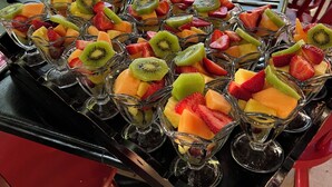 A table set with multiple fruit bowls containing sliced fruits like strawberries, kiwi, and cantaloupe.