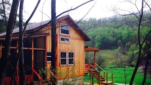 A wooden cabin with a porch and stairs leading to a deck.