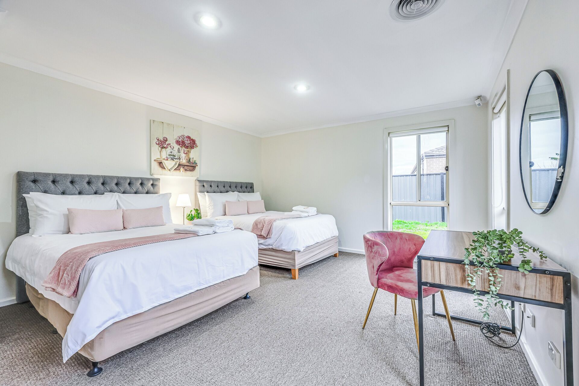 A bedroom with two beds, a desk, and a chair.