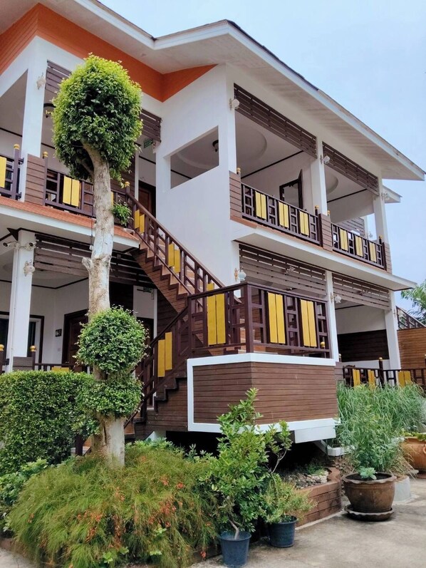 Un edificio de varios pisos con una escalera central, balcones y una variedad de plantas en macetas.