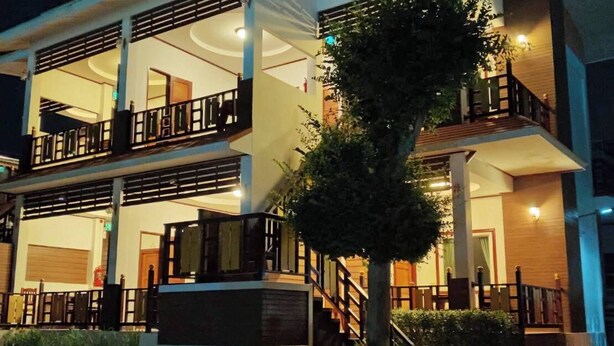 A two-story building with balconies, a staircase, and a well-lit entrance.