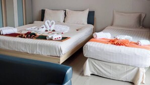 A hotel room with two beds, a blue sofa, and a small table with towels and a tray.