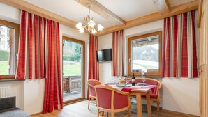 A dining area with a wooden table, red upholstered chairs, and a chandelier. - Apartment with wellness & Premium Card (Wildschönau)