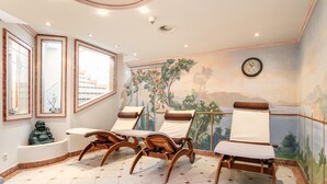 Ein Zimmer mit Fliesenboden, Holzsesseln, einer Badewanne und einem Wandgemälde einer Landschaft.
