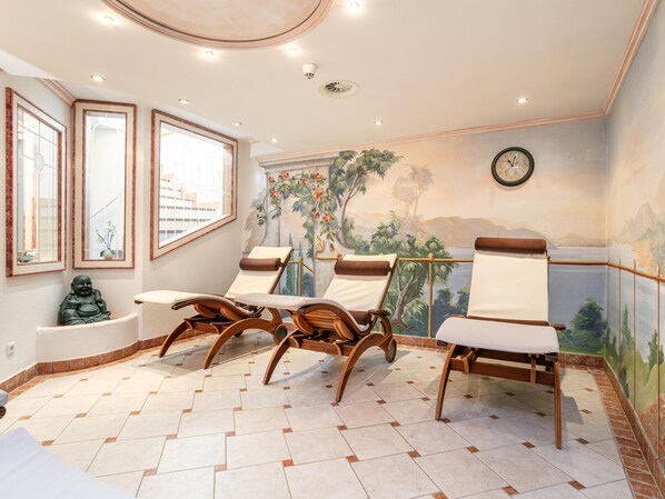 Una habitación con sillas de madera, una bañera y un mural de un paisaje tropical.
