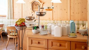 Cozinha com armários de madeira, uma tigela de frutas, um dispensador de leite e um lustre.