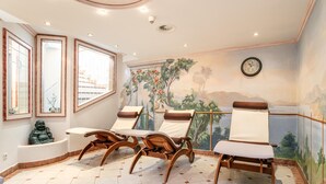 Um quarto com cadeiras de madeira, uma pequena estátua e um mural na parede.