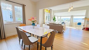 A spacious living area with a dining table, chairs, and a sofa. - StayAU 2BR Home w/ Stunning Views in Tasmania (Trevallyn)