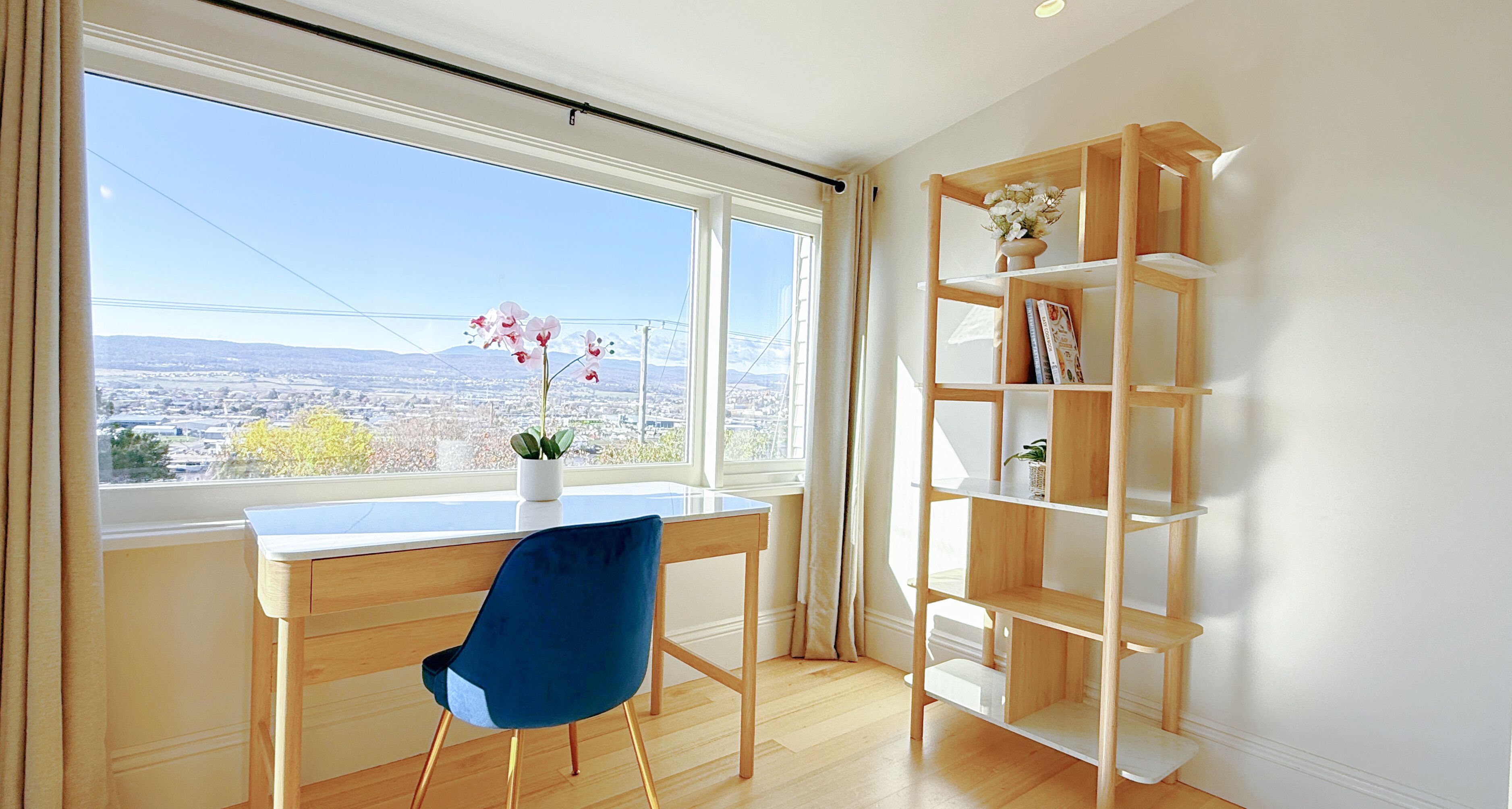 A room with a wooden desk, a blue chair, and a wooden bookshelf.