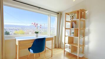 A room with a wooden desk, a blue chair, and a wooden bookshelf.