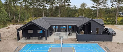 A modern building with a basketball court in front.