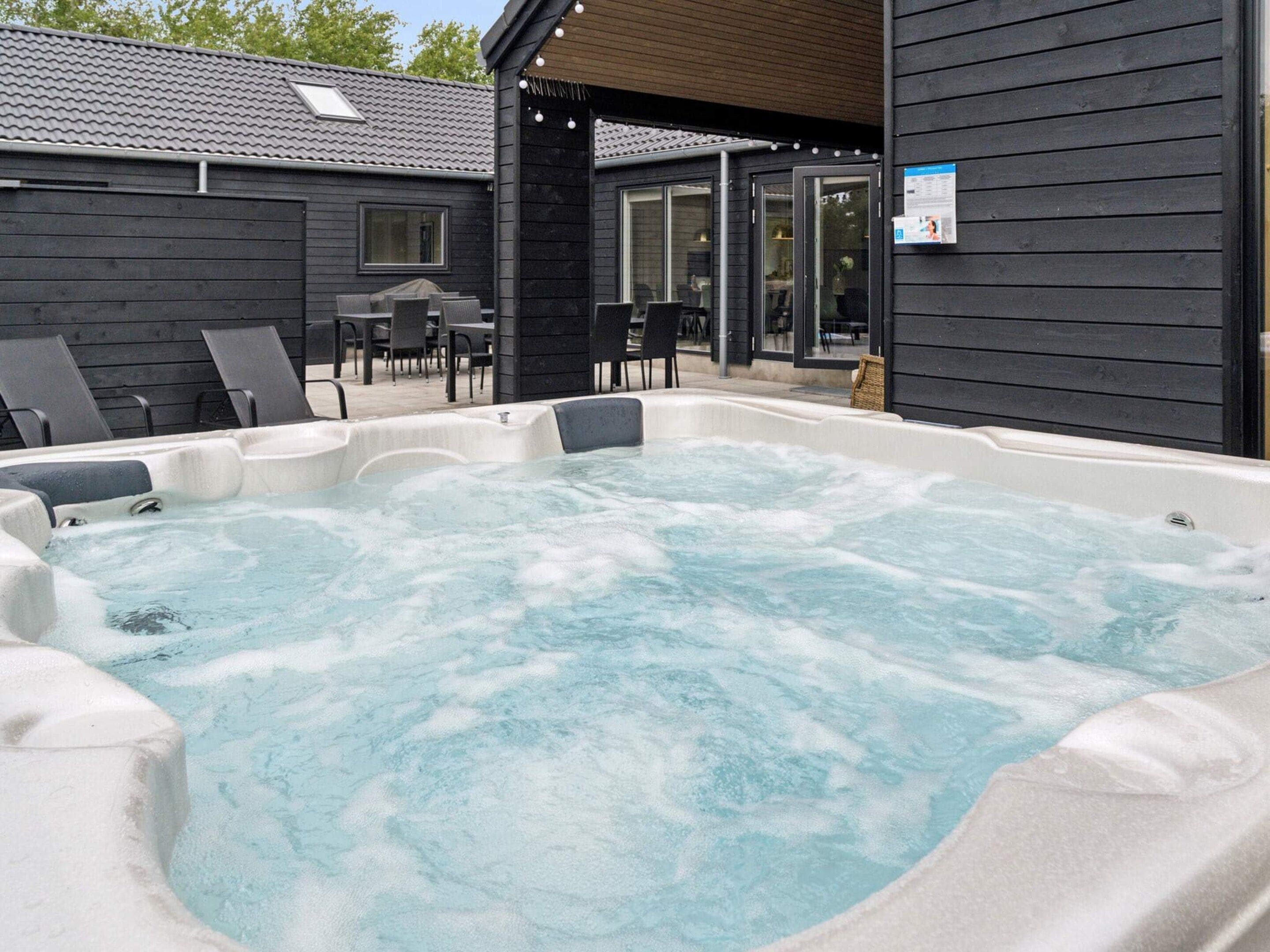 A hot tub area with lounge chairs and a covered patio.