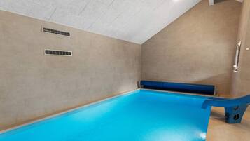 A swimming pool with a blue floor, a blue bench, and a wall-mounted handrail.