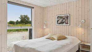 Un dormitorio con una cama grande, paredes de madera, una ventana y un cuadro enmarcado en la pared.
