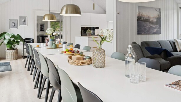 Un comedor moderno con una mesa larga, sillas e lámparas colgantes.
