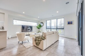 A modern living room with a sofa, armchair, coffee table, and a TV.
