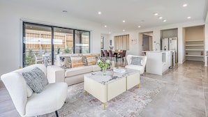 A spacious living room with a sofa set, a coffee table, and a dining area with chairs and a table. - StayAU 5BR Family Getaway GreaterGeelong in Duneed (Mount Duneed)