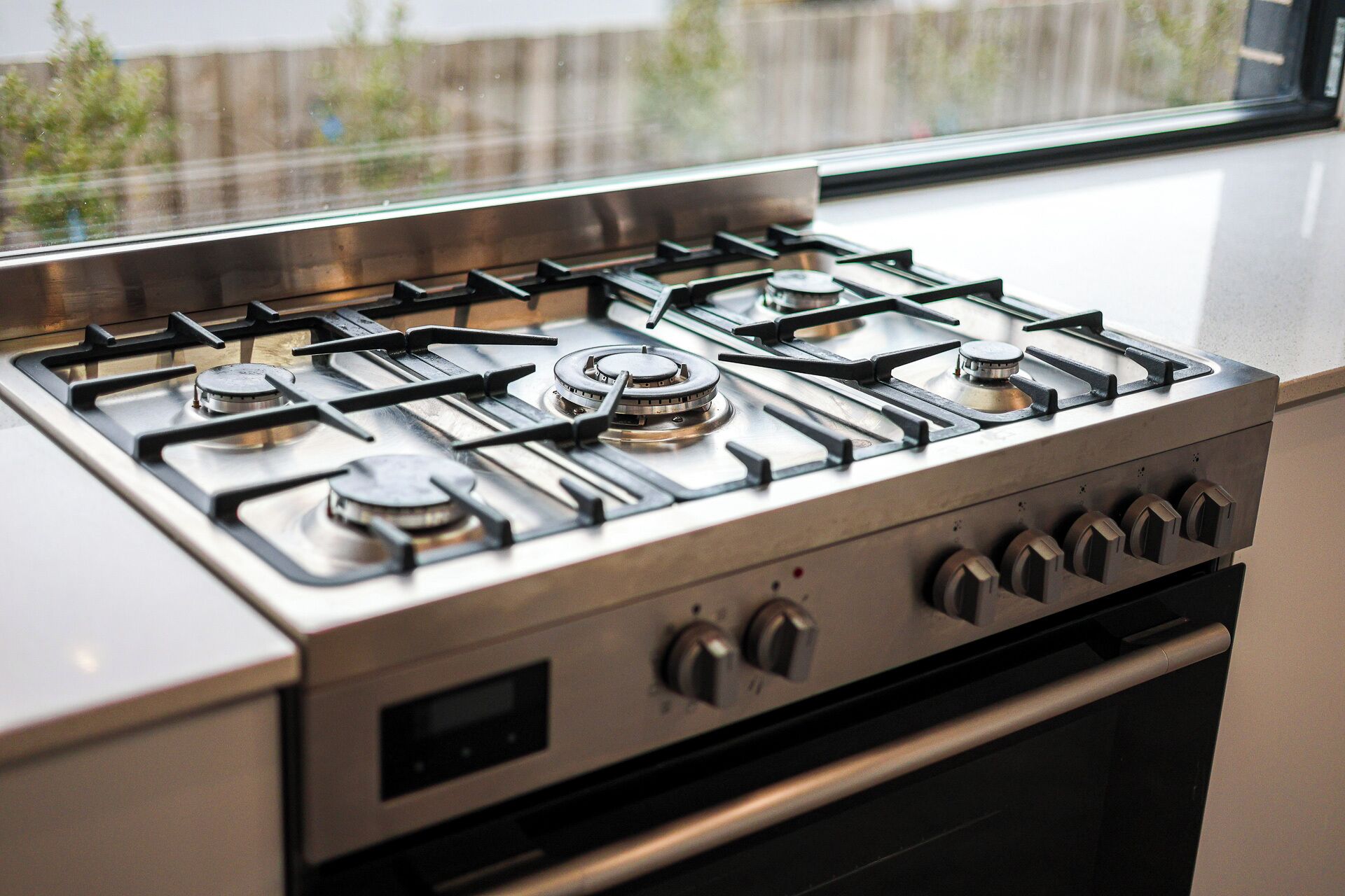 A stainless steel gas stove with four burners and a control panel with four knobs.